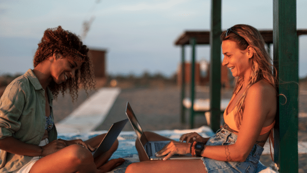 Two women working and laughing at a beach.