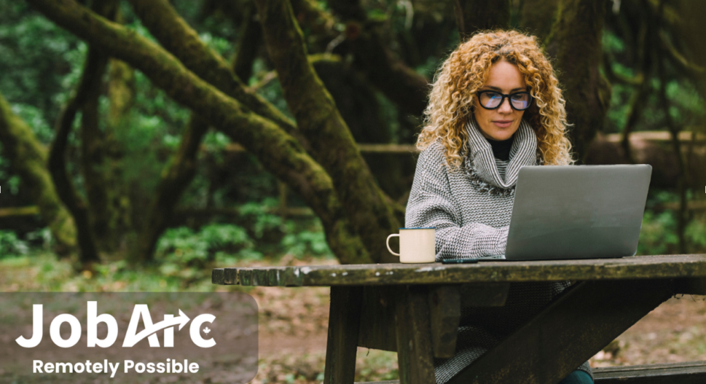 Woman works on a laptop from a picnic table.